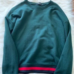 A green sweater with cute black and red cuffs.
